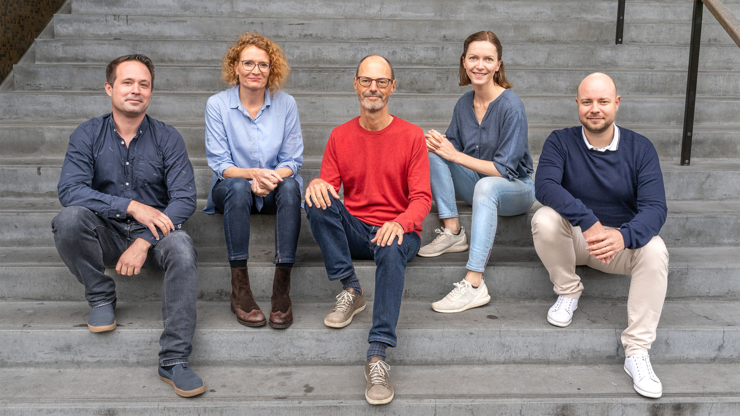 Das Team der Kommunikationsagentur diktum.ch sitzt auf der Freitreppe der Genossenschaft Kalkbreite in Zürich.